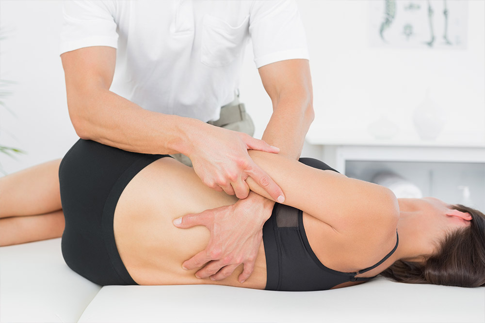 Female Patient at the physiotherapy doing physical exercises with her therapist, he gives her a medical massage